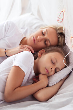 a woman laying on top of a bed next to a little girl, wearing white pajamas, having a good time, istock, elegant shot, with a white, comfortable, heartwarming, radiant morning light, stock image, full