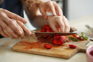 Close-Up of Hands Slicing Fresh Strawberries on a Wooden Cutting Board