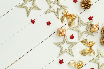 Golden and red festive star decorations against a white wooden background