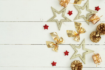 Golden and red festive star decorations against a white wooden background