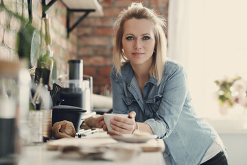 Portrait of a young woman enjoying a cup of coffee in the kitchen at home
