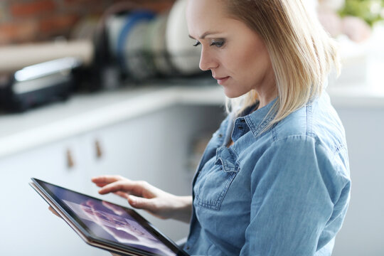 Image of young woman lworking on digital tablet at home