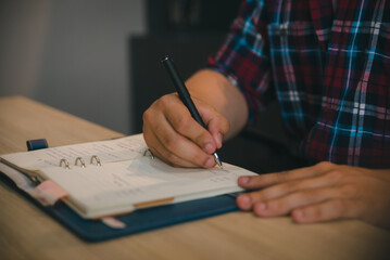 Planner write meeting agenda at Calendar, work online at home. Hand of man planning daily appointment and note holiday trip schedule in diary at business office desk.Calendar reminder event concept.