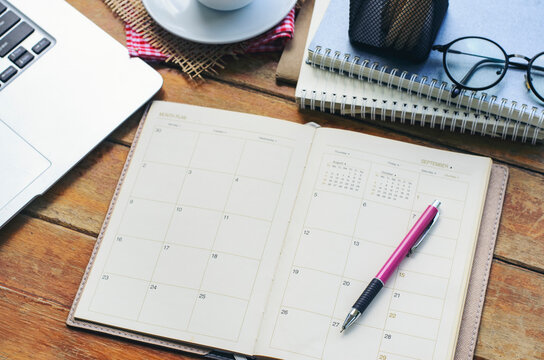 Agenda, planner book, laptop, pencil, and cup of coffee placed on office desk. Diary for organizer to plan timetable, daily appointment, and management job at room. Planner book and Calendar Concept