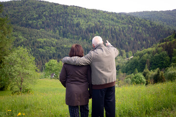 Fototapeta na wymiar Senior couple in love hugging in spring mountains