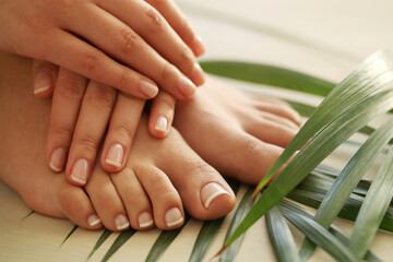 Perfect female hands with manicure on women’s legs 