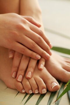 Perfect female hands with manicure on women’s legs 