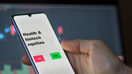 An investor's analyzing the health & biotech equities etf fund on screen. A phone shows the ETF's prices healthcare equity to invest