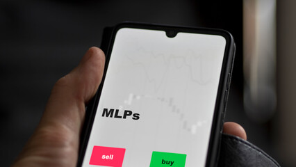 An investor's analyzing the MLPs etf fund on screen. A phone shows the ETF's prices mlps to invest