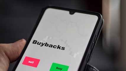 An investor's analyzing the buybacks etf fund on screen. A phone shows the ETF's prices stocks to invest