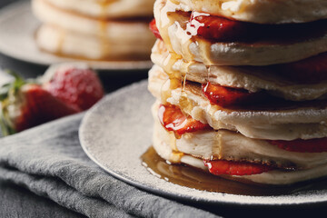 Beautifully decorated delicious sweet pancakes with strawberries and honey on the plate