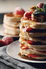 Beautifully decorated delicious sweet pancakes with strawberries and honey on the plate