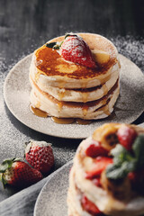 Beautifully decorated delicious sweet pancakes with fruits and honey on the plate