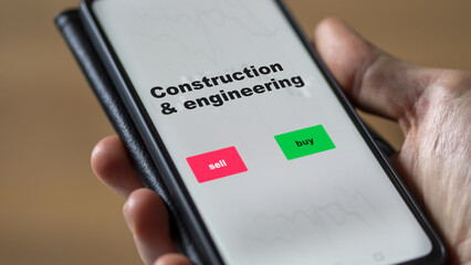 An investor's analyzing the construction & engineering etf fund on screen. A phone shows the ETF's prices construction and engineering to invest