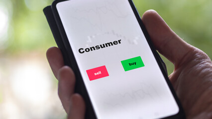 An investor's analyzing the consumer etf fund on screen. A phone shows the ETF's prices consumer to invest