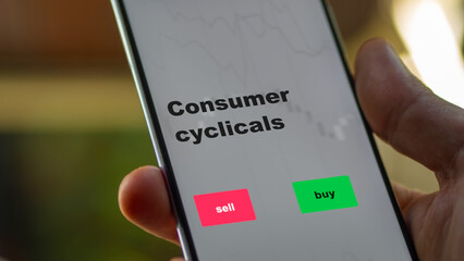 An investor's analyzing the consumer cyclicals etf fund on screen. A phone shows the ETF's prices consumer cyclicals to invest