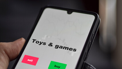 An investor's analyzing the toys & games etf fund on screen. A phone shows the ETF's prices stocks to invest