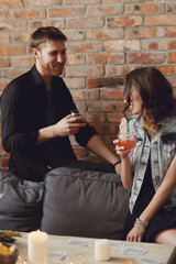 Young couple drinking drinks and talking at their friends' party