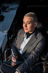 Business woman with short hair sits by the window and writes on a digital tablet with a stylus pen