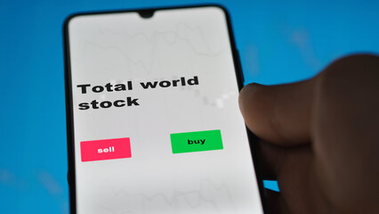 An investor's analyzing the total world stock etf fund on screen. A phone shows the ETF's prices global international exchange to invest