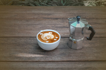Latte art with moka pot on wood background.