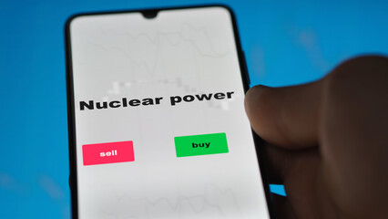 An investor's analyzing the nuclear power etf fund on screen. A phone shows the ETF's prices stocks to invest