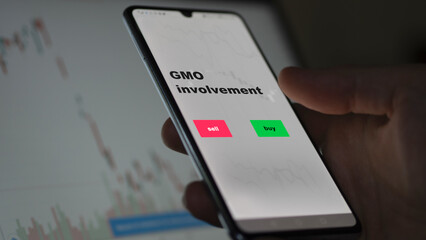 An investor's analyzing the GMO involvement etf fund on screen. A phone shows the ETF's prices gmo genetically modified organisms to invest