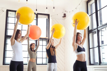 A group of fit young women in Pilates with colorful yoga balls
