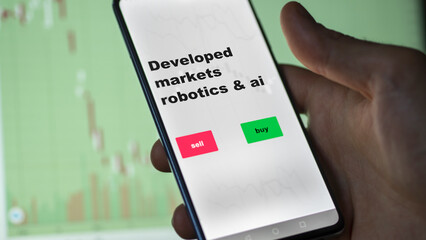 An investor's analyzing the developed markets robotics & ai etf fund on screen. A phone shows the ETF's prices stocks to invest