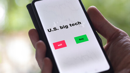 An investor's analyzing the U.S. big tech etf fund on screen. A phone shows the ETF's prices stocks to invest