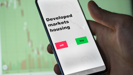 An investor's analyzing the stocks on screen. A phone shows the ETF's prices developed markets housing