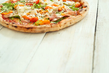 Picture of delicious hot whole pizza with vegetables on a wooden background