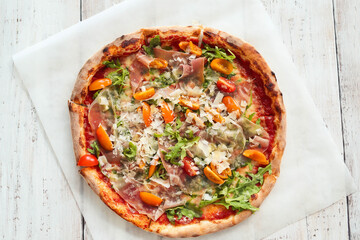 Picture of delicious hot whole pizza with vegetables on a wooden background