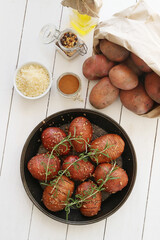 Delicious baked hot potato with rosemary and spices on a wooden background