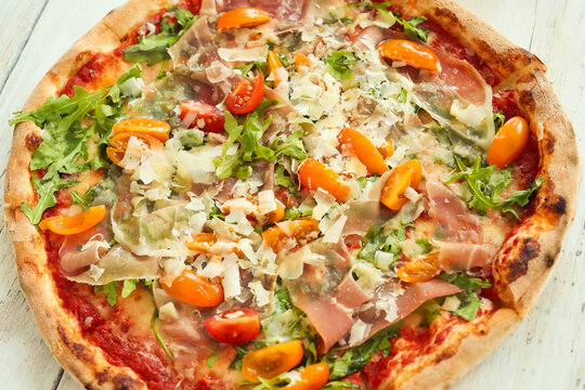 Picture of delicious hot whole pizza with vegetables on a wooden background