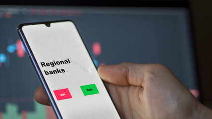 Regional banks, n investor's analyzing the stocks on screen. A phone shows the ETF's prices regional banks