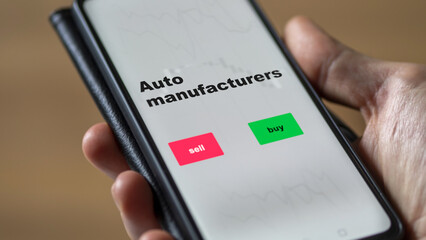 An investor's analyzing the stocks on screen. A phone shows the ETF's prices auto manufacturers