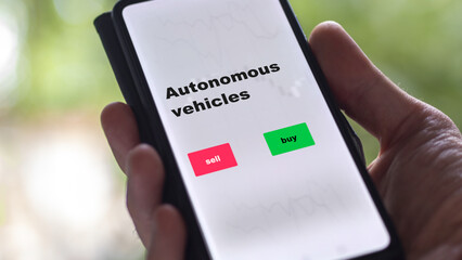 An investor's analyzing the stocks on screen. A phone shows the ETF's prices autonomous vehicles