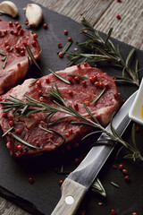 Raw fresh red meat with rosemary and spices on a black board