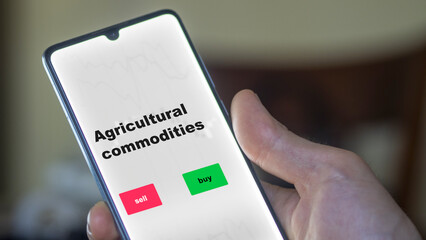 An investor's analyzing the stocks on screen. A phone shows the ETF's prices agricultural commodities