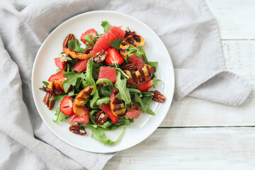 Summer yummy salad with grapefruit , strawberries, arugula and pecan nut in the white plate