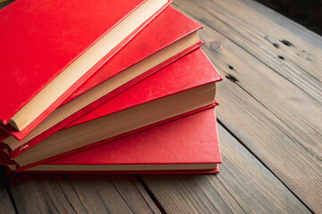 A fan of books. The red books are fanned on a wooden table. On the table are four books with a red...