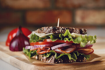 Close view of delicious fresh sandwich bread with tomatoes, cheese, lettuce, ham and onion on a...