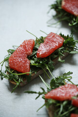 Close view of delicious Bruschetta (sandwiches) with arugula and slices of grapefruit on a white background