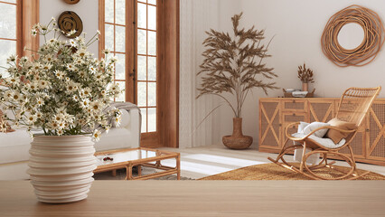 Wooden table top or shelf with pottery vase with daisies, wild flowers, over bohemian wooden living room in boho style, mediterranean interior design concept