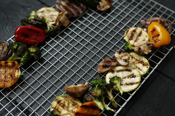 Delicious hot grilled food with broccoli, tomatoes cherry, peppers and zucchini on a black background