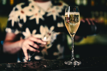 Bartender pouring champagne wine into glass in bar