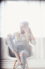 Photo of a beautiful young girl sitting in the chair and posing in a photo studio 