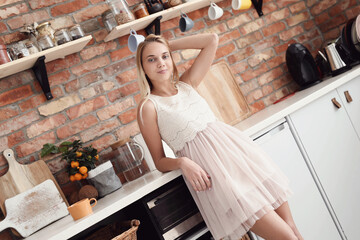 Photo of a young girl model posing in a beautiful dress in the kitchen