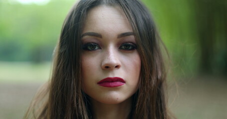 Portrait of serious young woman in 20s looking to camera in outdoors